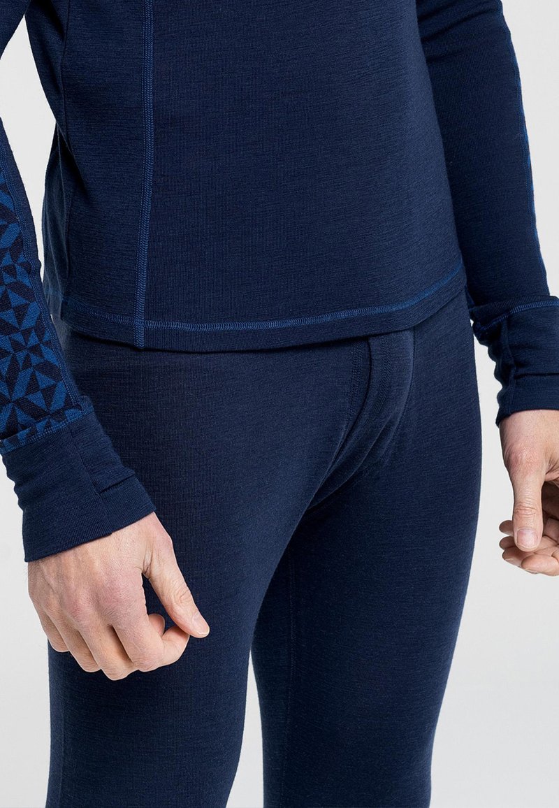 Marineblå atletisk top og leggings lavet af åndbart materiale. Toppen har en geometrisk mønstret ærme og en tæt pasform med sømløs syning.