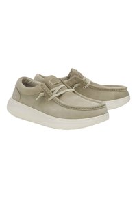 Zapatos de ante beige con puntera redondeada, diseño de cordones y suela de goma blanca. Presenta costuras a lo largo de los bordes y una etiqueta de marca en la lengüeta.