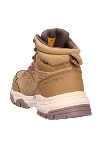 Bruine wandelschoen met een gevoerde kraag, getextureerde bovenkant en rubberen zool. Voorzien van veters en een logo aan de zijkant, ontworpen voor ruw terrein.