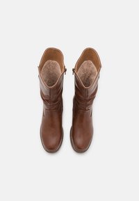 Bottes montantes en cuir marron avec une finition texturée, dotées d'une fermeture éclair latérale et d'une doublure intérieure douce et duveteuse.