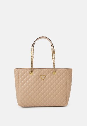 Beige quiltet tote-taske med guldfarvede detaljer, der har to kædehåndtag og en trekantet logoemblem foran.