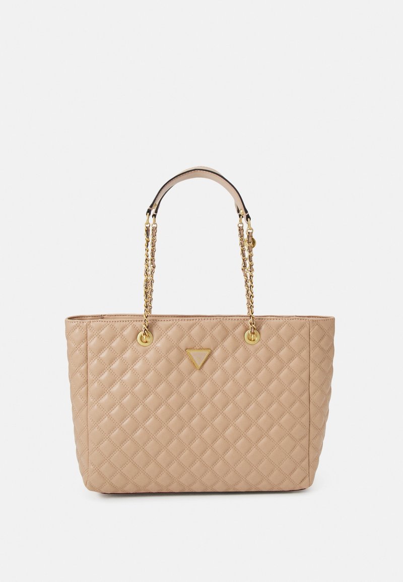 Sac cabas matelassé beige avec quincaillerie dorée, comprenant des poignées à double chaîne et un emblème de logo triangulaire sur le devant.