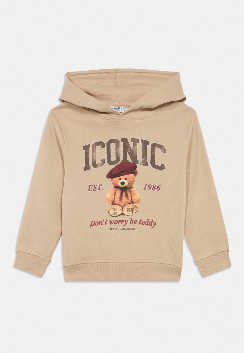 Beige children's hoodie with hood, graphic of a teddy bear wearing a beret, and text "ICONIC," "Don't worry be teddy," and established 1986.