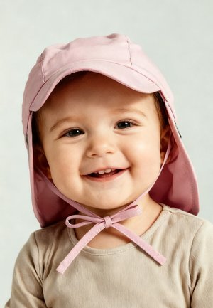 Smiling toddler wearing a light pink sun hat tied under the chin and a beige shirt against a plain background.