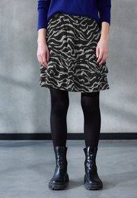 Sort og grå zebra-printet lagdelt nederdel med elastisk talje, parret med sorte tætte strømpebukser og kraftige sorte ankelstøvler.