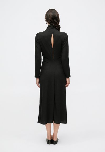Fekete kötött midi ruha hosszú ujjakkal, hátul kulcslyuk részlettel és alakra szabott derékrésszel. Sima textúra, bővülő szegéllyel.