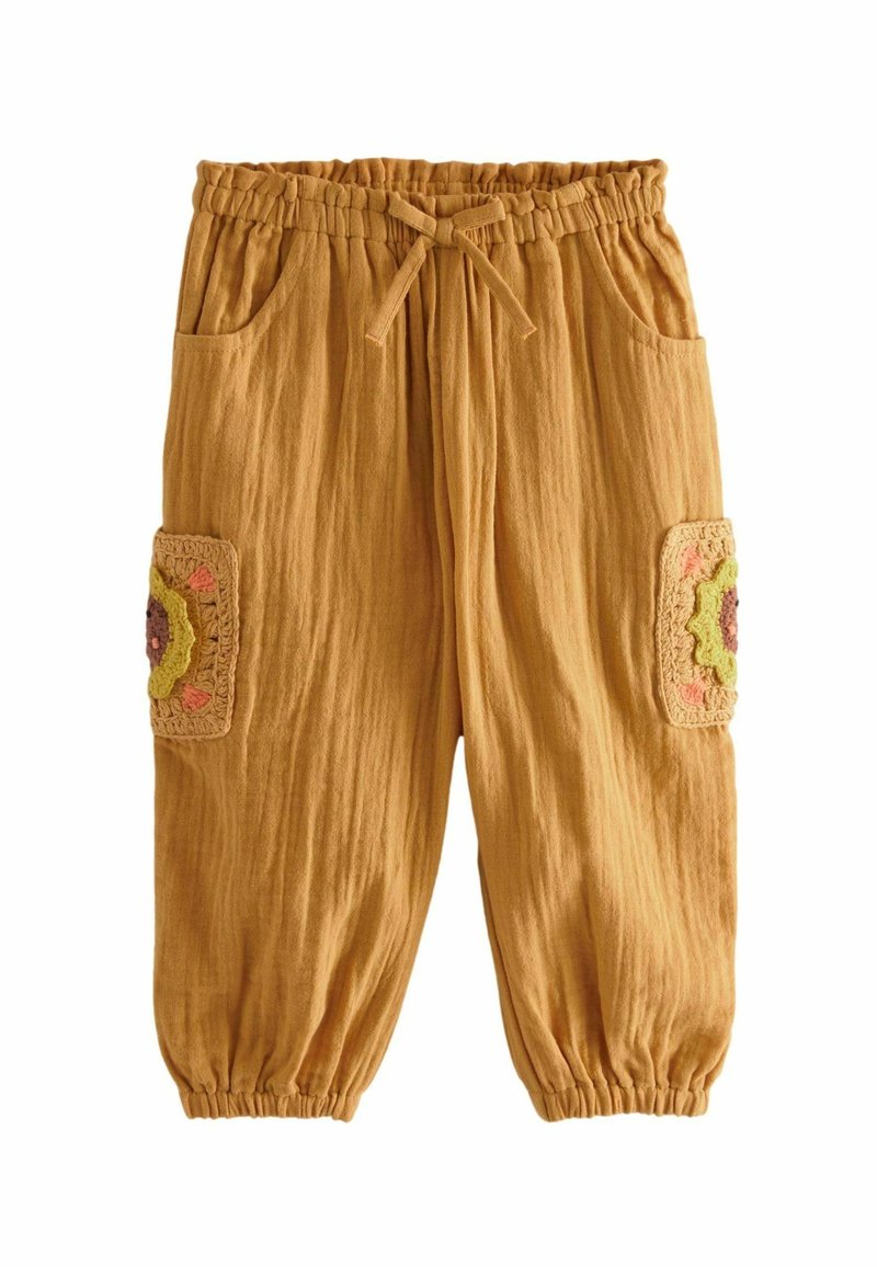 Pantalon pour tout-petit couleur rouille avec taille élastique, cordon de serrage, poignets froncés, poches latérales et appliques de fleurs au crochet sur les jambes.