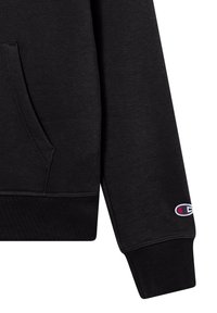 Sudadera negra con un acabado texturizado, bolsillo canguro, puños acanalados y pequeño logo bordado en la manga.