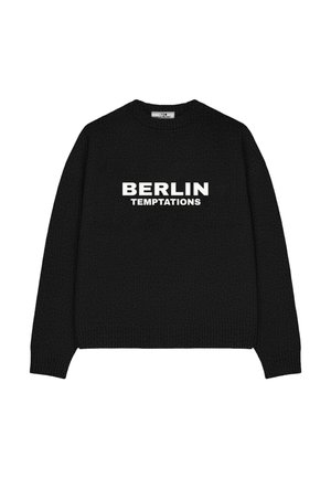 Person with short hair facing away wearing a black sweater with "VERTERE PERMANENT TEMPORARY LOVE AS LIABILITY" text on the back.