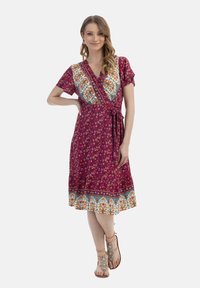 Rochie înfășurată de culoare magenta închis, cu modele florale, mâneci scurte și talie cu șnur. Detaliu de bordură colorat cu accente albastre și portocalii.