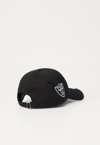 Gorra de béisbol negra de algodón, con un logotipo de los Raiders bordado en blanco y una correa ajustable en la parte posterior. Textura suave.