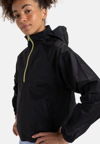 Black windbreaker jacket with a half-zipper, elastic cuffs, and a textured finish, featuring a bright yellow zipper detail.