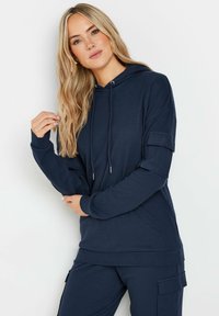 Felpa blu navy a coste con cappuccio e cordoncino, maniche lunghe e tasca laterale. Texture morbida, vestibilità rilassata e design casual.