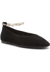 Zapato plano de ante negro con puntera puntiaguda y detalle de cadena en el tobillo, que presenta un perfil bajo y una textura suave. Suela de goma flexible para mayor comodidad.