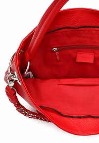 Czerwona torebka z teksturowanej skóry, przestronne wnętrze wyłożone tkaniną, kieszeń na zamek i metalowe ozdoby.