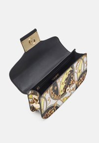 Prostokątna torebka na ramię z czarnym wnętrzem, złotym zatrzaskiem oraz zewnętrzną ozdobą w postaci wzoru łańcucha kwiatowego w czerni, bieli i żółci.