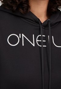 Sudadera con capucha negra de tela suave con un logo blanco que dice "O'NEIL". Incluye cordones en el escote para un ajuste ajustable.