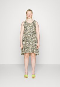 Vestido sem mangas com padrão floral, de decote redondo, base preta e flores de várias cores. Acompanhado por sandálias verdes de slide.