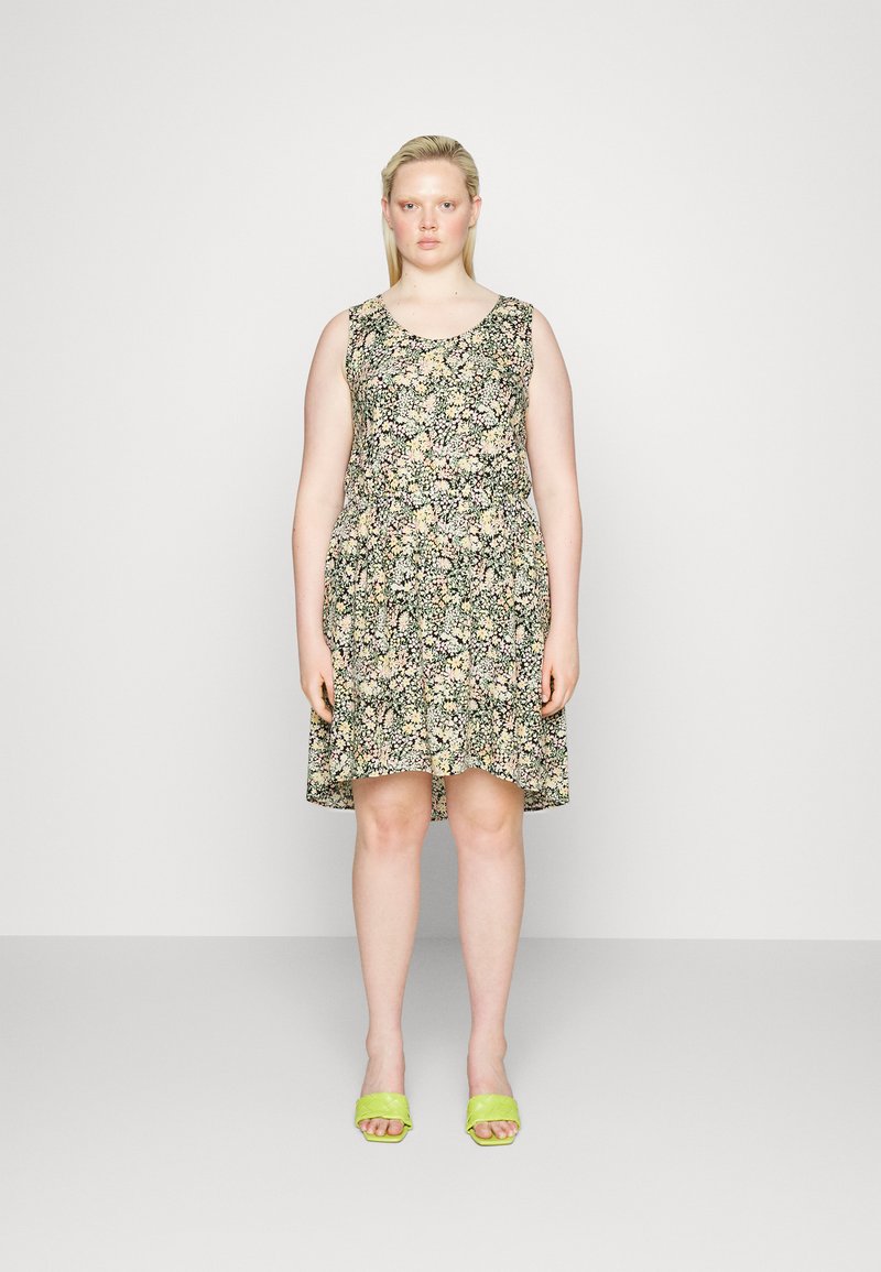 Vestido sem mangas com padrão floral, de decote redondo, base preta e flores de várias cores. Acompanhado por sandálias verdes de slide.