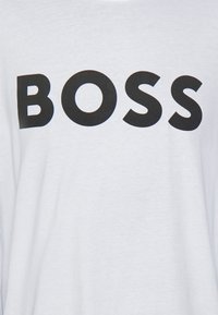 Bílá látka s velkými černými písmeny, které se přesně uprostřed tisknou slovo "BOSS".