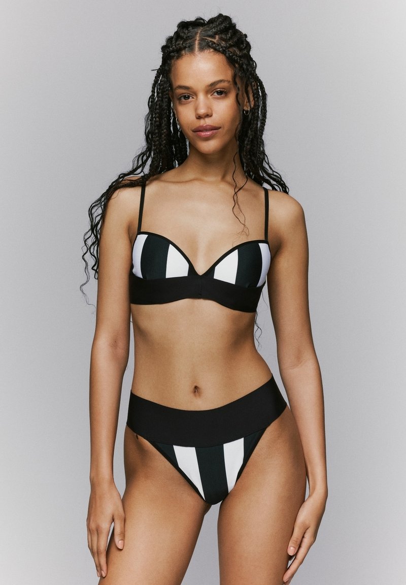 Zwart-wit gestreepte bikini met een gestructureerde bralette-top met dunne bandjes en een hoog opgesneden broekje, met een gladde textuur.