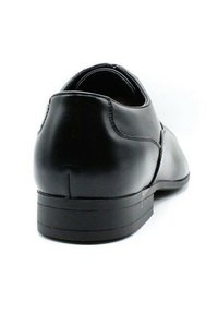 Chaussure en cuir noir avec un dos arrondi, un talon bas et un minimum de détails de coutures. Texture lisse et design épuré, convient aux occasions formelles.