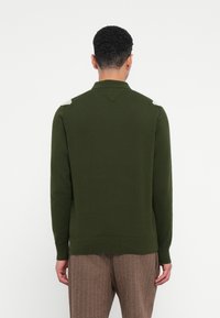 Grüner Strickpullover mit Kragen, strukturiertem Stoff und Schulterakzenten. Mit einem V-Ausschnitt und gerippten Bündchen und Saum.