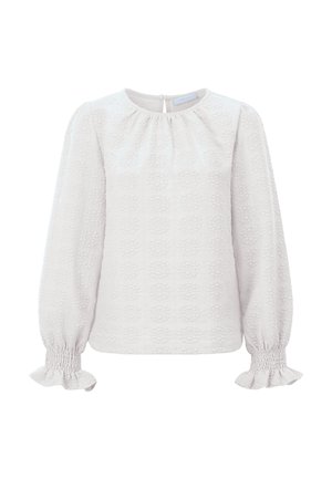 Blouse blanche texturée à manches longues, avec un col froncé et des poignets à volants smockés. Présente un motif floral embossé sur tout le tissu.