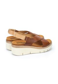 Sandalias de cuero marr�ón con correas cruzadas y correas ajustables en el talón. Presentan una plataforma de color crema con textura acanalada y detalles cosidos.