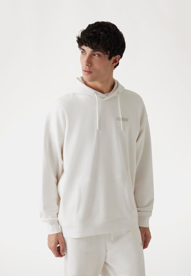 Valge kapuutsiga sweatshirth, millel on eesmine tasku ja nöör. Rinnal on peen logo. Kanga tekstuur on pehme ja sile.