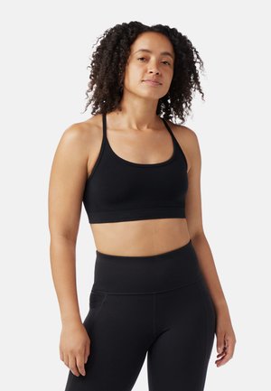Sort sports-bh med scoop-neck, tynde stropper og et bredt, støttende bånd. Sammen med højtaljede sorte leggings med sømløst design.