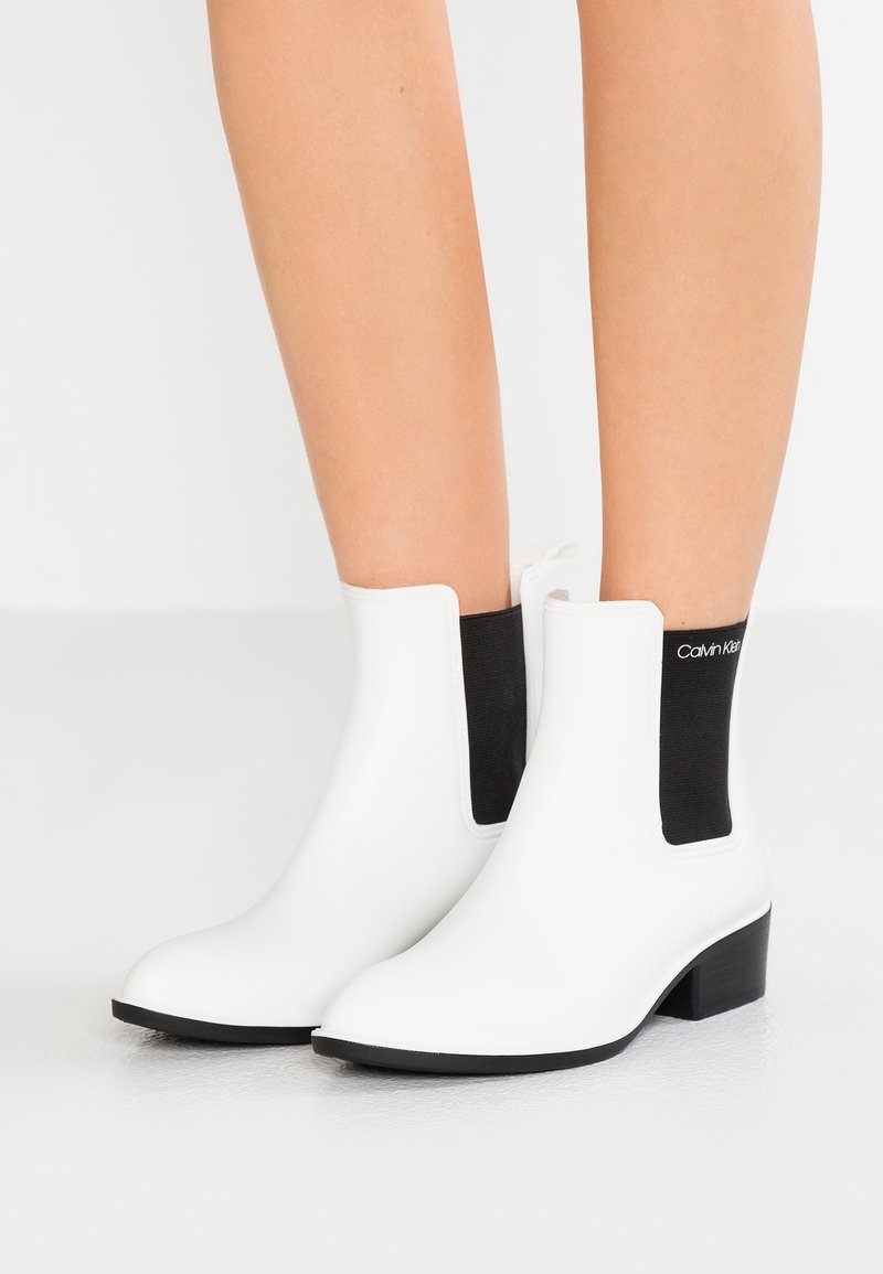 Botas Chelsea blancas con paneles laterales elásticos negros, de un material sintético suave, puntera afilada y tacón bajo de bloque.
