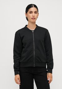 Čierna prešívaná bomber bunda s rebrovanými manžetami a golierom, s predným zipsom a jednofarebným dizajnom, vyrobená z textúrovanej látky.