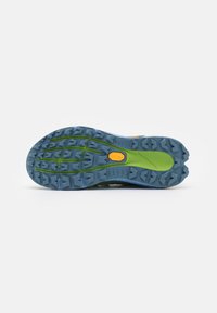 Maille de trail avec une semelle en caoutchouc bleu et vert, dotée de crampons agressifs et d'un logo Vibram pour une meilleure adhérence.