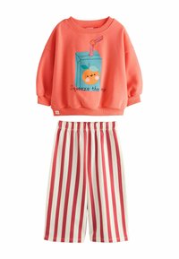 Koral sweatshirt med grafik af en appelsinjuiceboks og teksten "Squeeze the day." Matchende hvide shorts med røde vertikale striber.