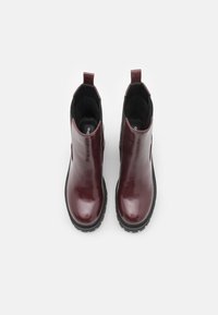 Botine burgundii cu un finisaj lucios, panouri elastice laterale și tălpi de cauciuc texturat negru. Dispune de bucle pentru a fi ușor de încălțat.