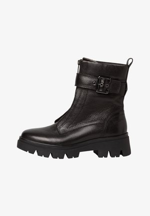 Black leather ankle boot with textured finish, side zipper, and adjustable strap featuring a metallic buckle. Chunky, ridged sole.