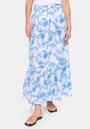 Fustă maxi florală din bumbac alb cu un model de flori albastre, având un talie elastică și o margine volanată. Asortată cu sandale plate maro.