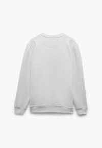 Sudadera blanca con cuello redondo, mangas largas, puños y dobladillo de canalé. Textura suave, diseño sencillo y sin logotipos ni patrones visibles.