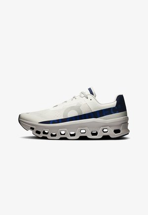 Trkaća obuća s prozračnom bijelom mrežicom na gornjem dijelu, plavim logotipom i robusnim sivim srednjim dijelom s heksagonalnim izrezima za ublažavanje.