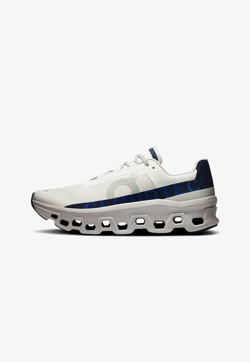 Buty biegowe z przewiewną, białą siateczką u góry, niebieskimi detalami z logo oraz masywną szarą podeszwą środkową z heksagonalnymi wycięciami dla lepszego amortyzacji.