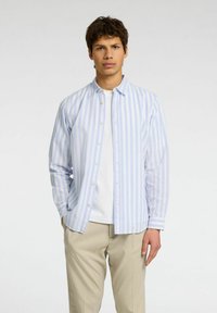 Vaaleansininen ja valkoinen raidallinen pitkähihainen paita, joka on valmistettu sileästä kankaasta, napitettu etuosa ja klassinen kaulus, yhdistettynä beigeihin housuihin.