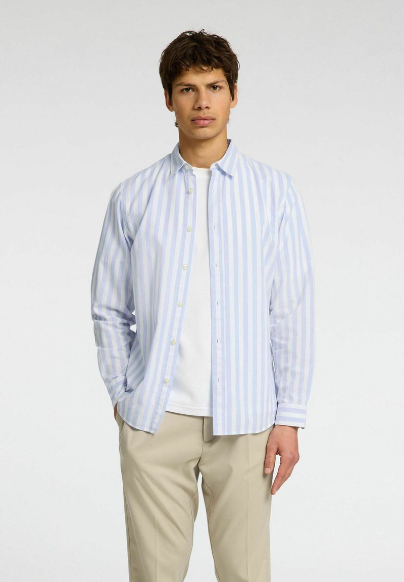 Vaaleansininen ja valkoinen raidallinen pitkähihainen paita, joka on valmistettu sileästä kankaasta, napitettu etuosa ja klassinen kaulus, yhdistettynä beigeihin housuihin.