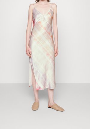 Dopasowana, bezrękawnikowa sukienka midi z pastelowym wzorem tie-dye, rozcięciem z boku oraz beżowymi plecionymi butami wsuwanymi na stojącej osobie.