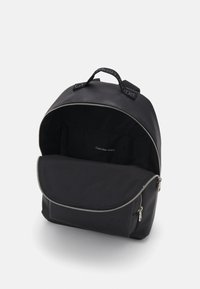 Zaino nero con esterno testurizzato, chiusura con zip e un ampio interno. Presenta una maniglia e un dettaglio con logo in rilievo.