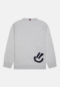 Sudadera gris con cuello redondo. Presenta un logo de sonrisa negro elevado en el lado izquierdo y puños y dobladillo acanalados.
