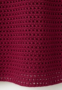 Gros plan d’un tissu tricoté bordeaux texturé avec un motif de tissage ouvert et des petits trous visibles partout.