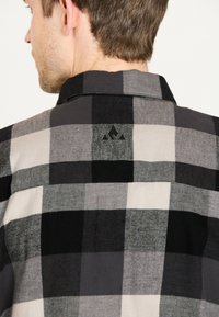 Zwart en grijs geruit overhemd met een zachte textuur, knoopsluiting kraag en een klein logo op de achterkant. Het is ontworpen in een relaxte pasvorm.
