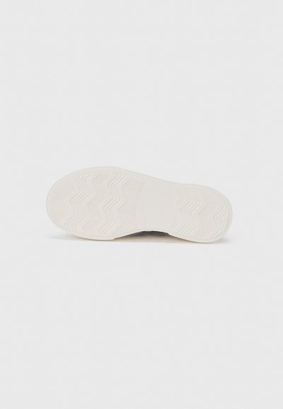 Semelle de chaussure de sport en caoutchouc blanc avec motif en zigzag, texture lisse et logo circulaire près du talon. Dispose d'un bout arrondi et d'un design plat.