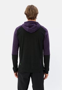 Felpa con maniche lunghe nera con maniche raglan viola e cappuccio coordinato, dotata di una tasca con zip sul lato. Tessuto morbido.